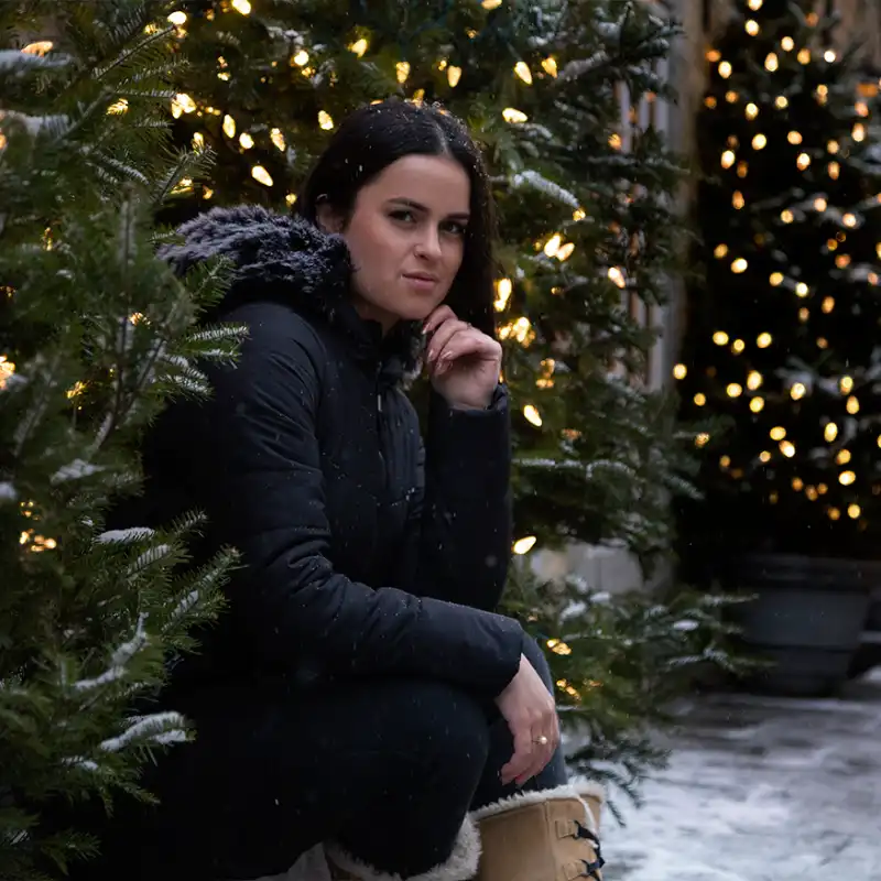 Our model wears the winter jacket SPARKLING black sitting next to a Christmas tree-44690