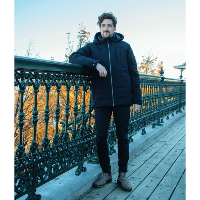 Our model wears the men's winter jacket SUIT black on a terrace. 43718
