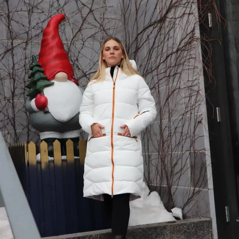 Notre modèle porte le manteau d'hiver NEST blanc-orange dans un décor de Noel