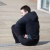 Homme portant le manteau BASE de couleur noir, utilisant la poche arrière du manteau - 43705