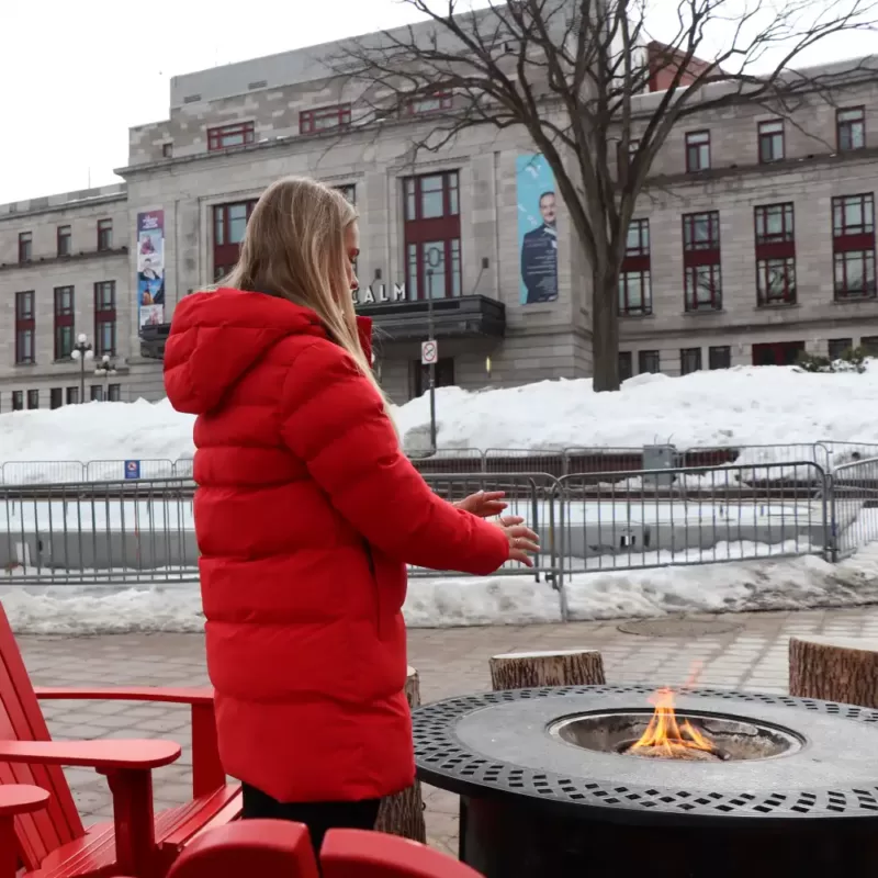 Our model wears the winter jacket SLACK pekin warming up by a fire.